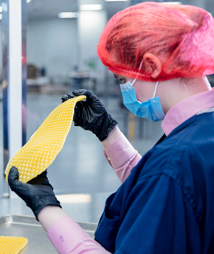 An employee wearing a hairnet and facemask holding up the rubber mold for our Edison Jolts