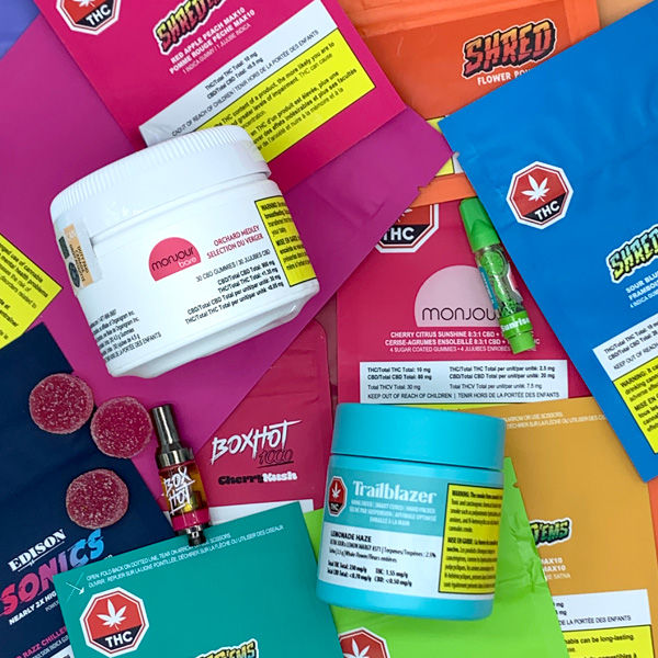 A close up image of a pile of Organigram recreational products including jars of cannabis, gummy pouches and vapes