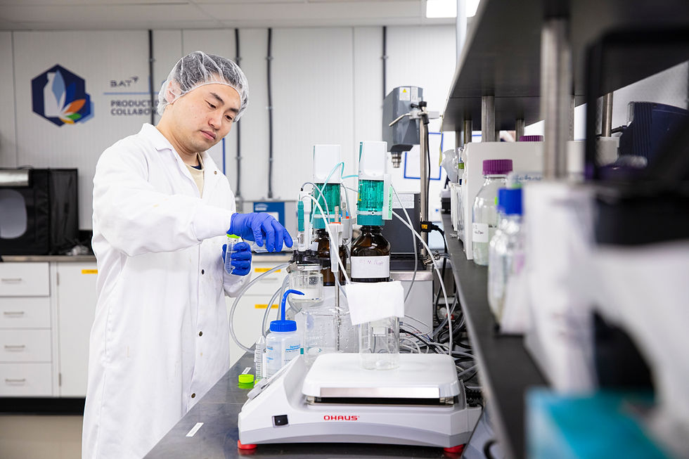 An image of a lab technician conducting some measurements, there are scales and various beeker in front of him, the BAT logo can be seen in the background