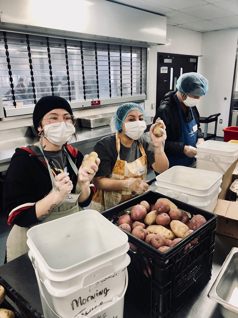 An image of three Organigram employees peeling potatoes while working a local volunteer event, the employees are in hair nets and masks