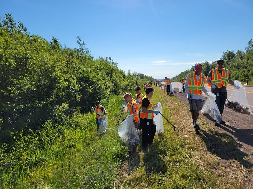 Organigram employees cleaning trash from the side of a highway in high-visibility vests.